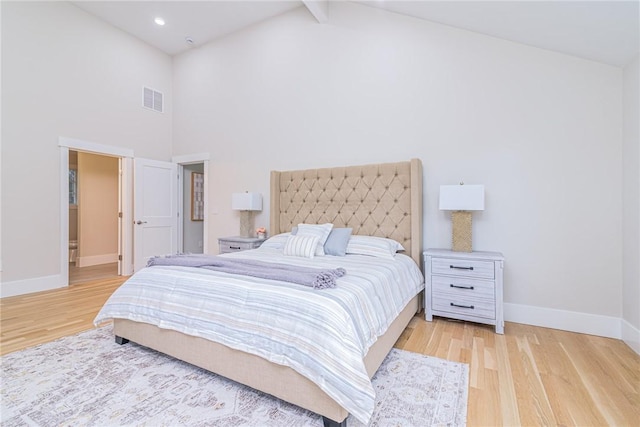 bedroom featuring beam ceiling, high vaulted ceiling, and light wood-type flooring