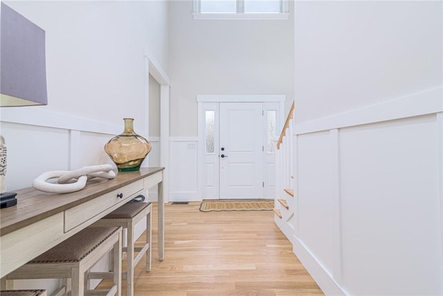 entryway with a towering ceiling and light wood-type flooring