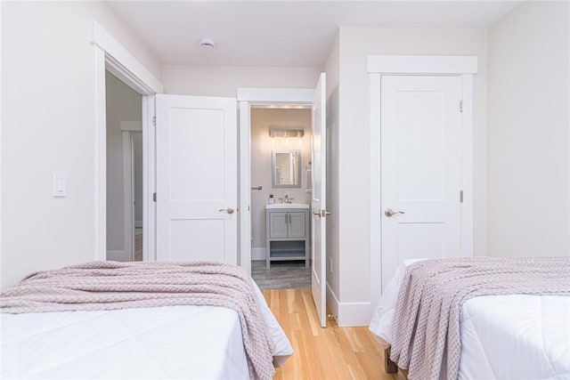 bedroom featuring ensuite bath and light wood-type flooring