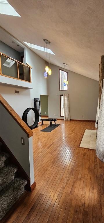 exercise room with vaulted ceiling, hardwood / wood-style floors, and a textured ceiling