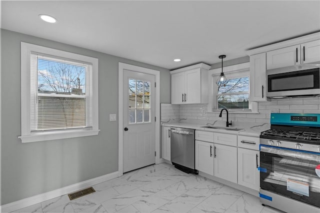 kitchen featuring sink, white cabinetry, tasteful backsplash, pendant lighting, and stainless steel appliances