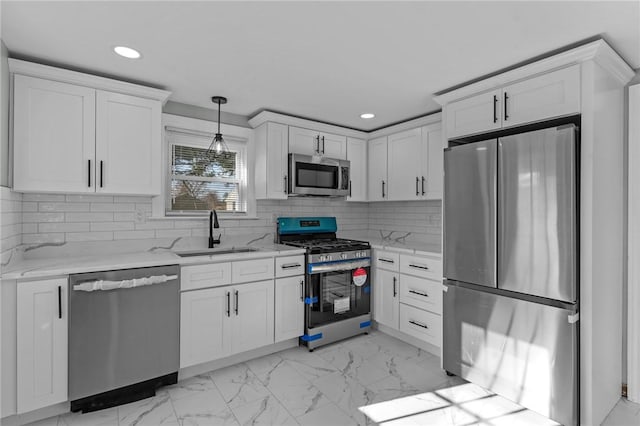 kitchen with pendant lighting, sink, white cabinets, and appliances with stainless steel finishes