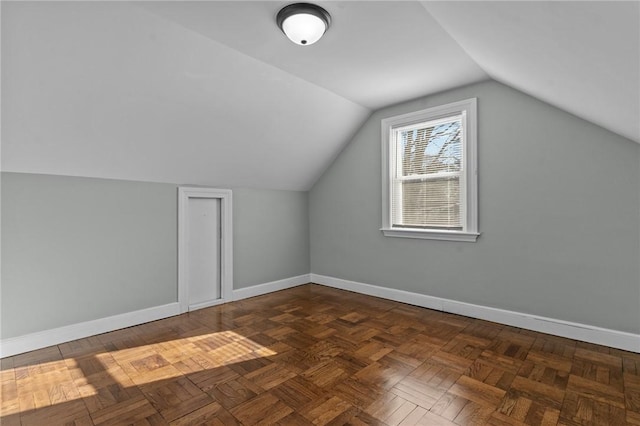 additional living space featuring dark parquet flooring and vaulted ceiling