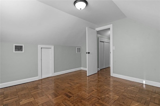 additional living space featuring lofted ceiling and dark parquet flooring