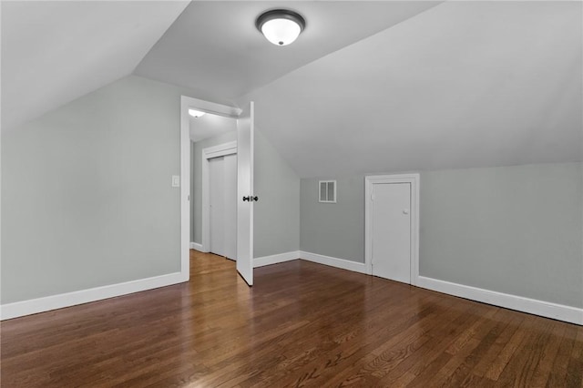 additional living space with dark wood-type flooring and vaulted ceiling