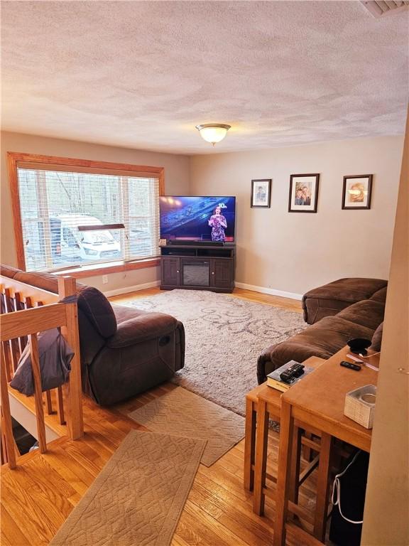 living room with light hardwood / wood-style floors and a textured ceiling