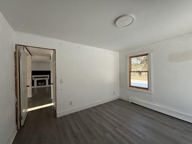 unfurnished room with dark wood-type flooring and a baseboard radiator