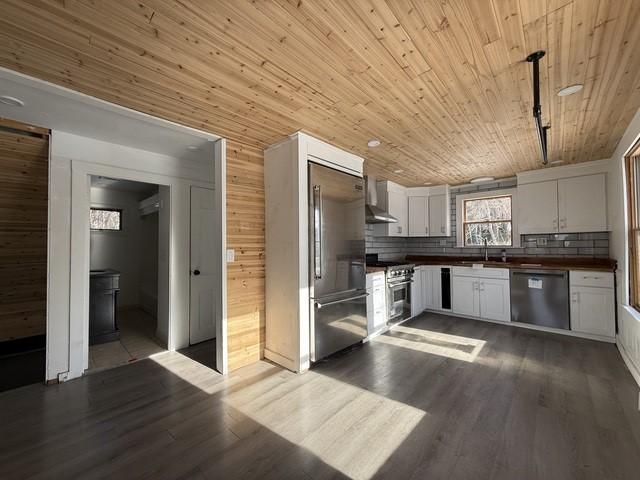 kitchen featuring white cabinetry, wall chimney range hood, wooden ceiling, and premium appliances