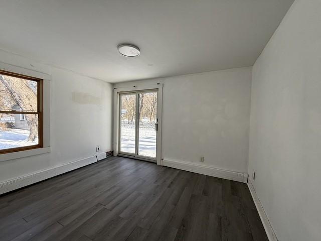 unfurnished room featuring a baseboard radiator and dark hardwood / wood-style flooring