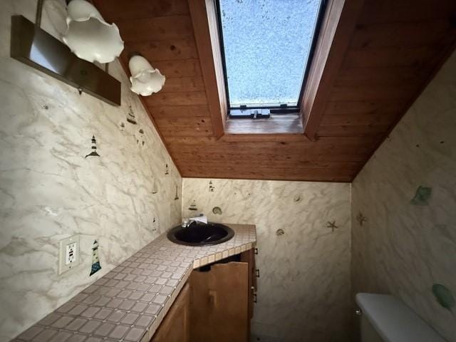 bathroom with wood ceiling, vanity, lofted ceiling with skylight, and toilet