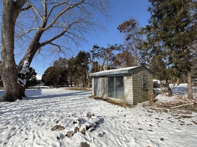 yard layered in snow featuring an outdoor structure