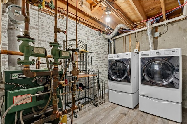 laundry room with hardwood / wood-style flooring, brick wall, and separate washer and dryer