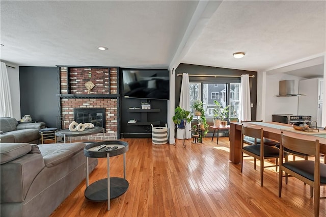 living room featuring hardwood / wood-style flooring, a fireplace, and beamed ceiling