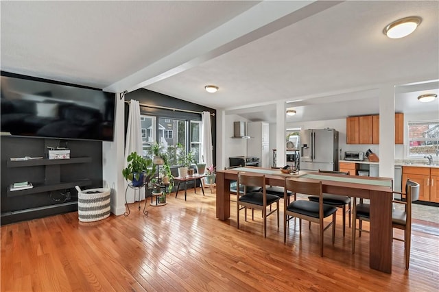 dining space with lofted ceiling, sink, and light wood-type flooring