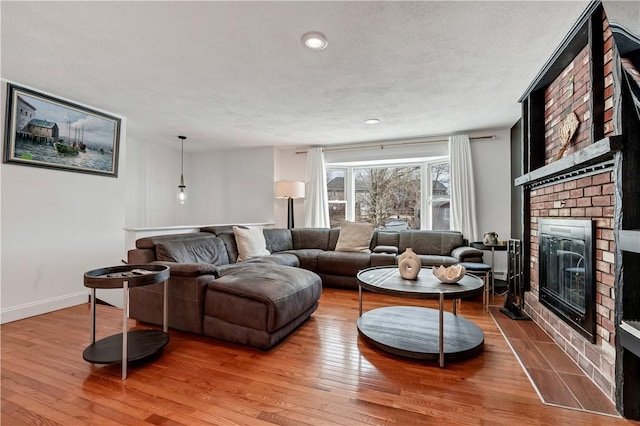 living room featuring hardwood / wood-style flooring, a brick fireplace, and a textured ceiling