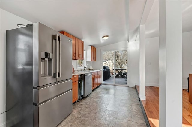 kitchen with sink, vaulted ceiling, stainless steel appliances, and light stone countertops