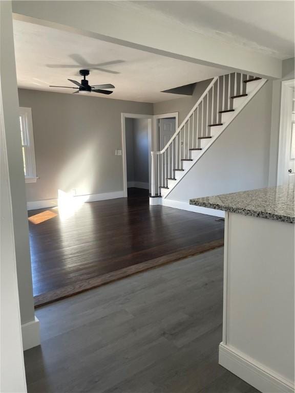 unfurnished living room featuring dark wood-type flooring and ceiling fan