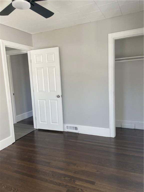 unfurnished bedroom featuring ceiling fan, dark hardwood / wood-style flooring, and a closet