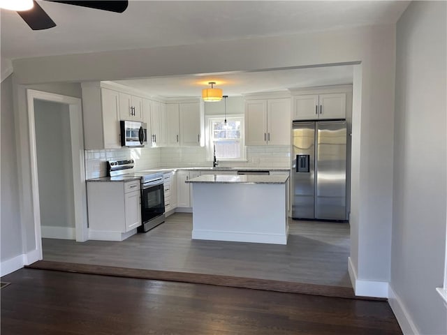 kitchen featuring backsplash, stainless steel appliances, hanging light fixtures, and white cabinets