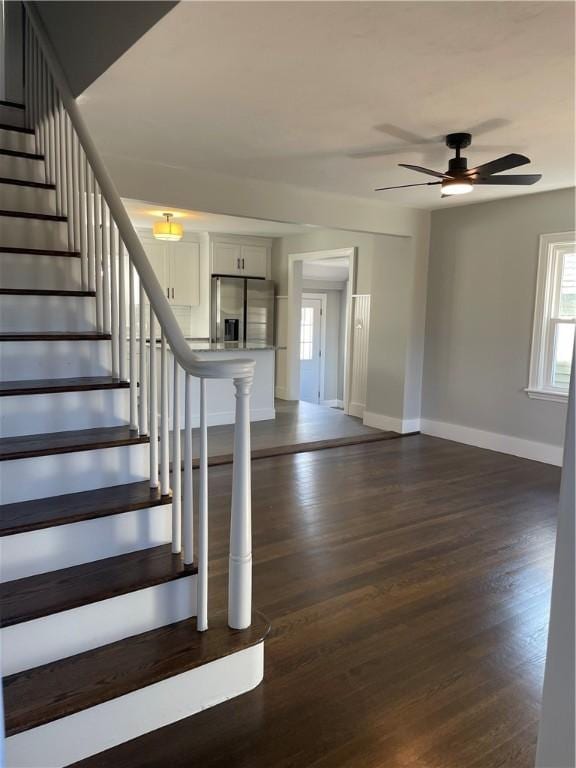 staircase with ceiling fan, baseboards, and wood finished floors