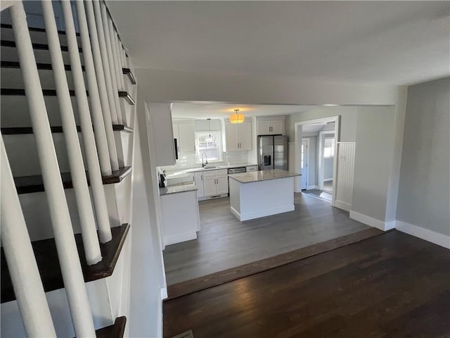 kitchen featuring dark wood-type flooring, white cabinetry, a center island, stainless steel fridge with ice dispenser, and decorative backsplash