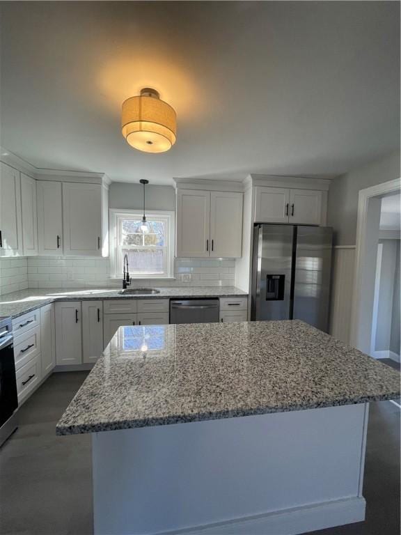 kitchen with sink, appliances with stainless steel finishes, light stone counters, white cabinets, and decorative backsplash