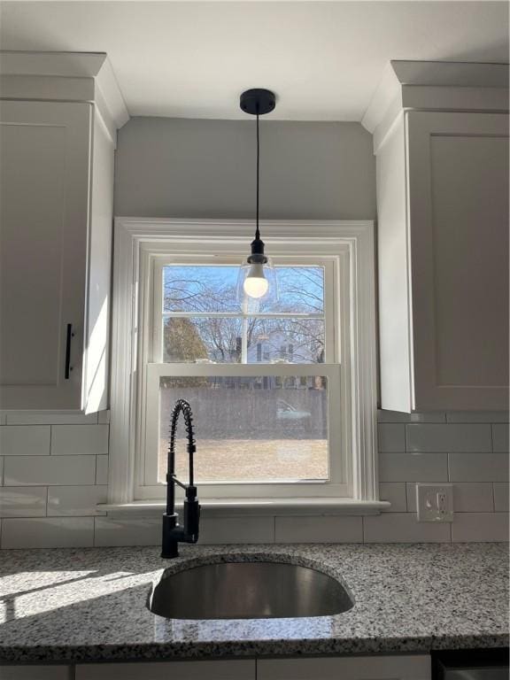 details featuring dark stone countertops, sink, white cabinetry, and decorative backsplash