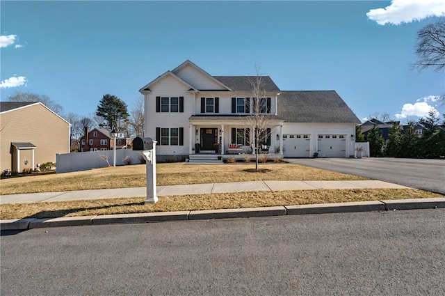 view of front of home with fence, a porch, a front lawn, a garage, and aphalt driveway