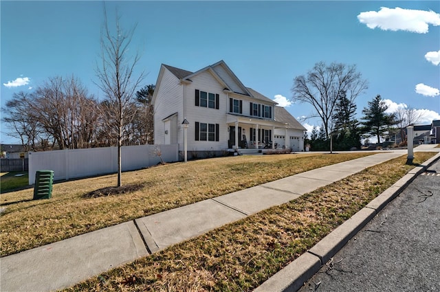 view of front facade with driveway, a front lawn, a garage, and fence