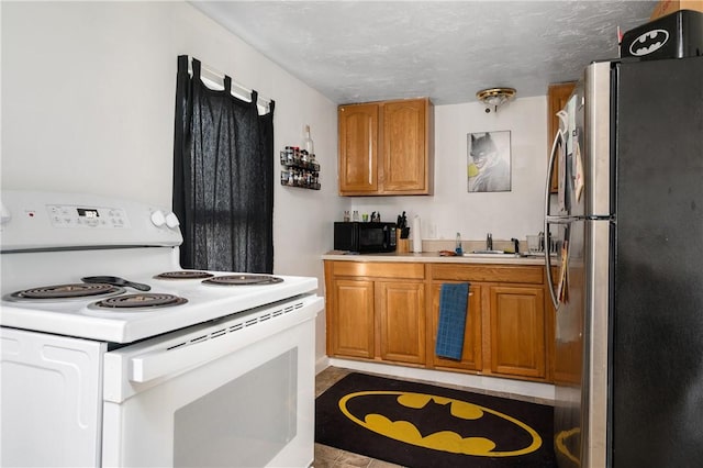 kitchen featuring sink, stainless steel fridge, and white electric range oven