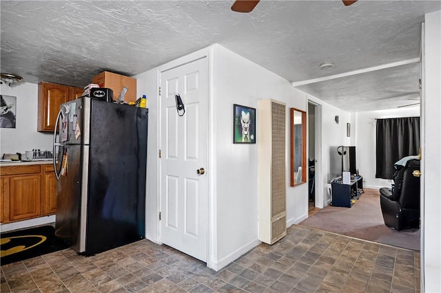 kitchen featuring stainless steel refrigerator, dark carpet, and a textured ceiling