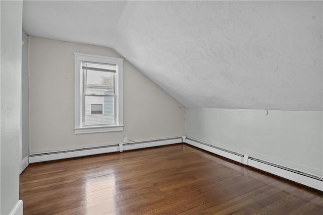 bonus room featuring vaulted ceiling, hardwood / wood-style floors, a textured ceiling, and a baseboard heating unit