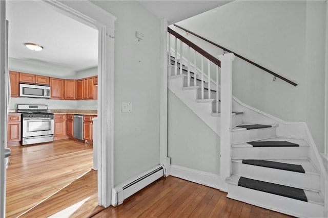 staircase featuring wood-type flooring and baseboard heating