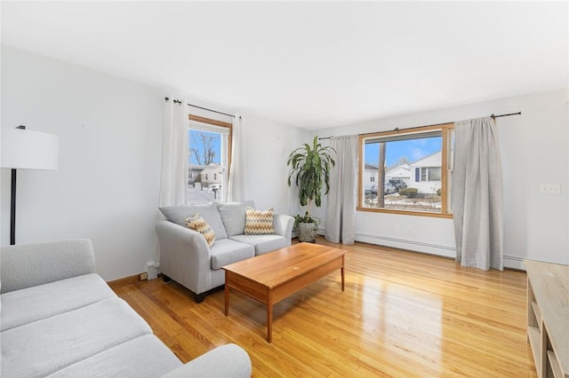 living room featuring a healthy amount of sunlight, light hardwood / wood-style flooring, and a baseboard heating unit