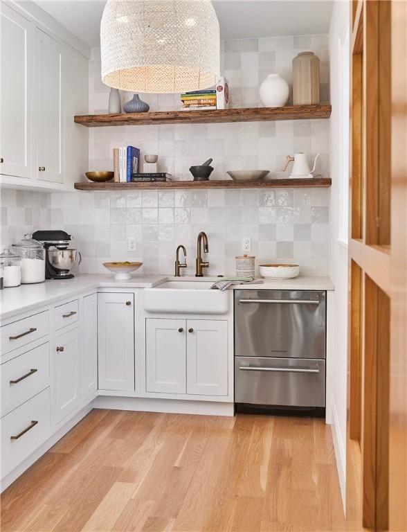 bar with dishwasher, white cabinetry, sink, decorative backsplash, and light hardwood / wood-style floors