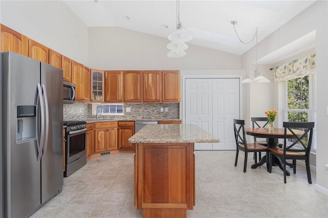 kitchen featuring stainless steel appliances, a kitchen island, glass insert cabinets, and decorative light fixtures