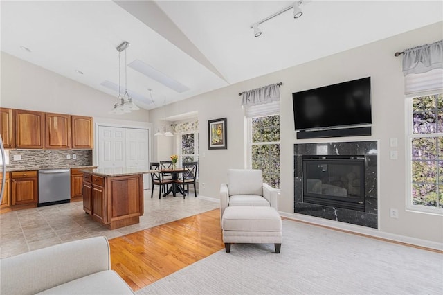 living room with a high end fireplace, lofted ceiling, light wood-style floors, and baseboards