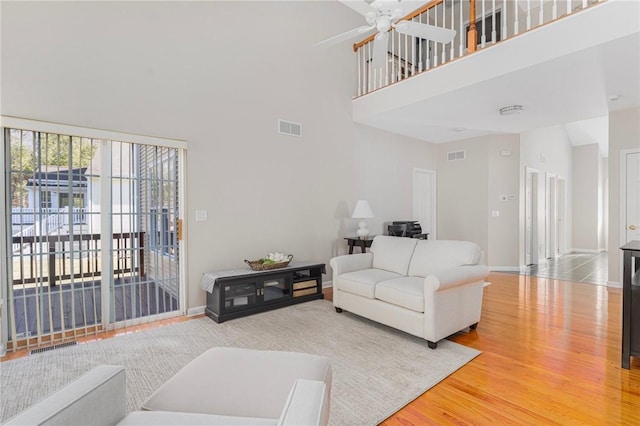 living room featuring a high ceiling, visible vents, and wood finished floors