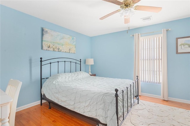 bedroom with baseboards, visible vents, ceiling fan, and wood finished floors