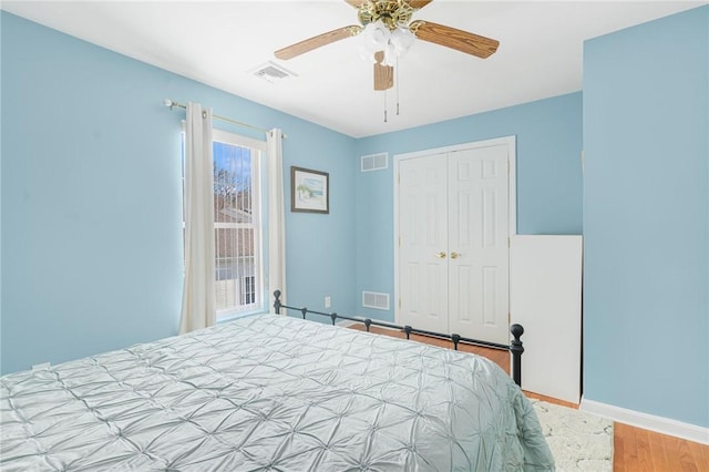 bedroom with a closet, visible vents, baseboards, and wood finished floors