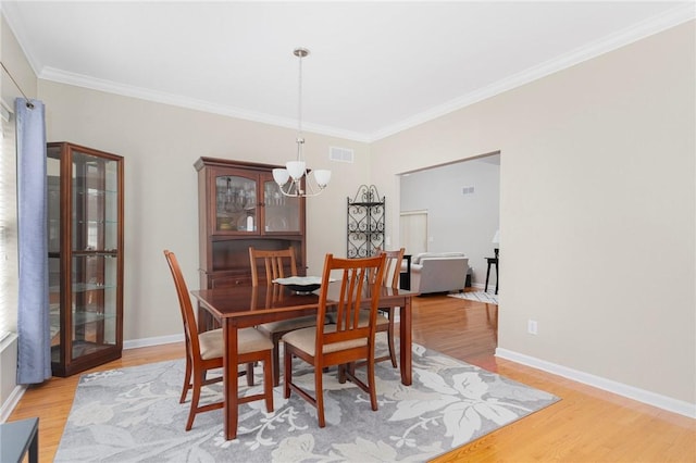 dining area with light wood-style floors, a chandelier, and visible vents