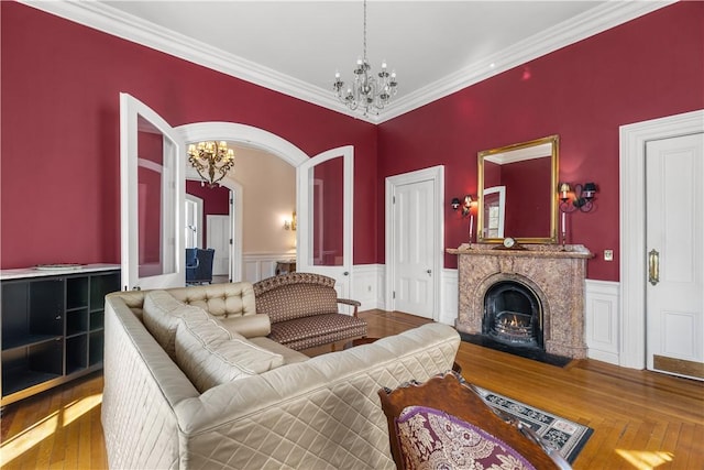 living room featuring hardwood / wood-style flooring, a fireplace, crown molding, and a notable chandelier