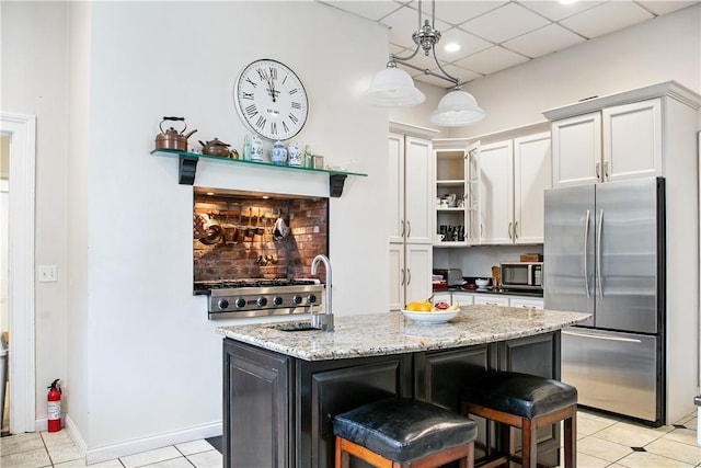 kitchen with a breakfast bar, light stone counters, a center island with sink, appliances with stainless steel finishes, and white cabinets