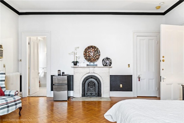 bedroom featuring parquet floors, ornamental molding, radiator, and a high end fireplace