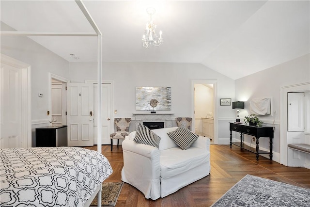 bedroom with vaulted ceiling, an inviting chandelier, ensuite bathroom, and a high end fireplace