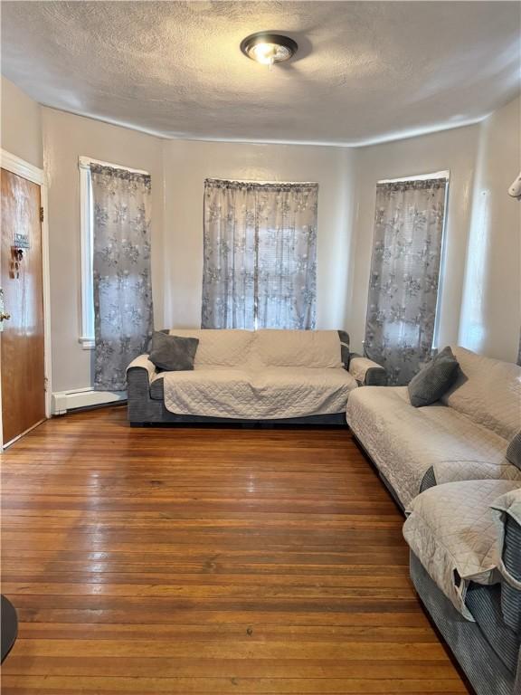 living room with hardwood / wood-style floors, a textured ceiling, and baseboard heating