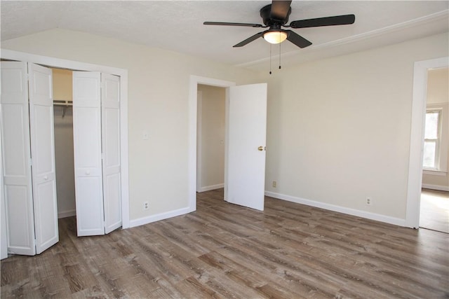 unfurnished bedroom with ceiling fan, lofted ceiling, hardwood / wood-style floors, and a closet