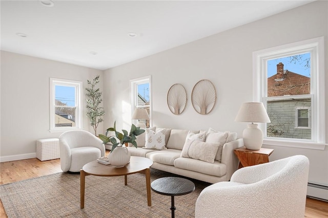 living room with a baseboard heating unit and light wood-type flooring