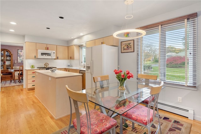 dining area with a baseboard heating unit, sink, and light wood-type flooring