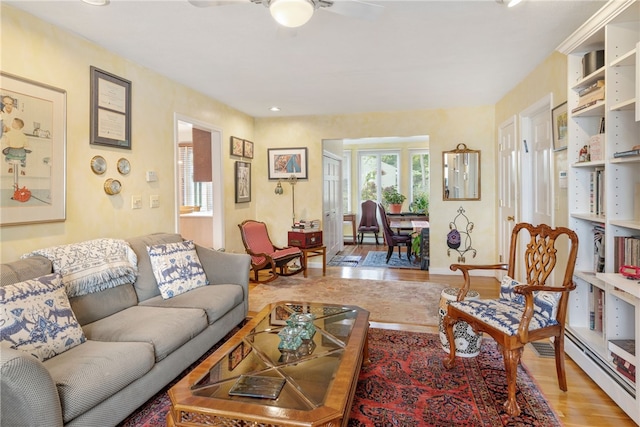 living room featuring a baseboard radiator, light hardwood / wood-style floors, and ceiling fan